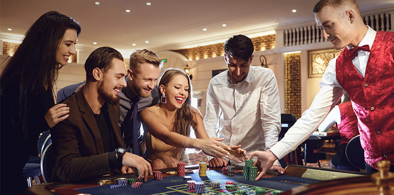 Grupo de pessoas diverte-se a jogar em redor de uma mesa de casino